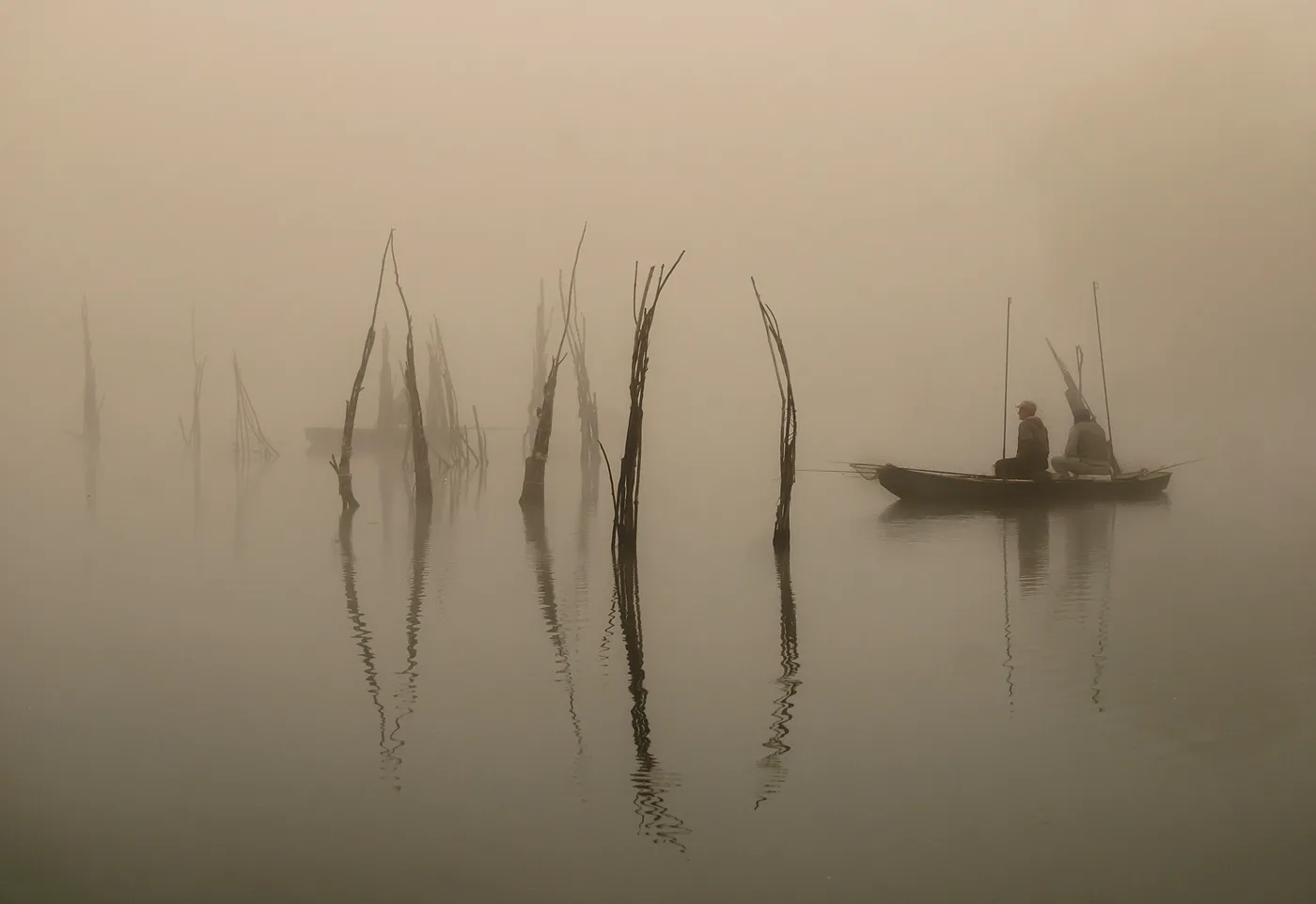 Pescador con caña en la orilla al amanecer, silueta sobre el mar